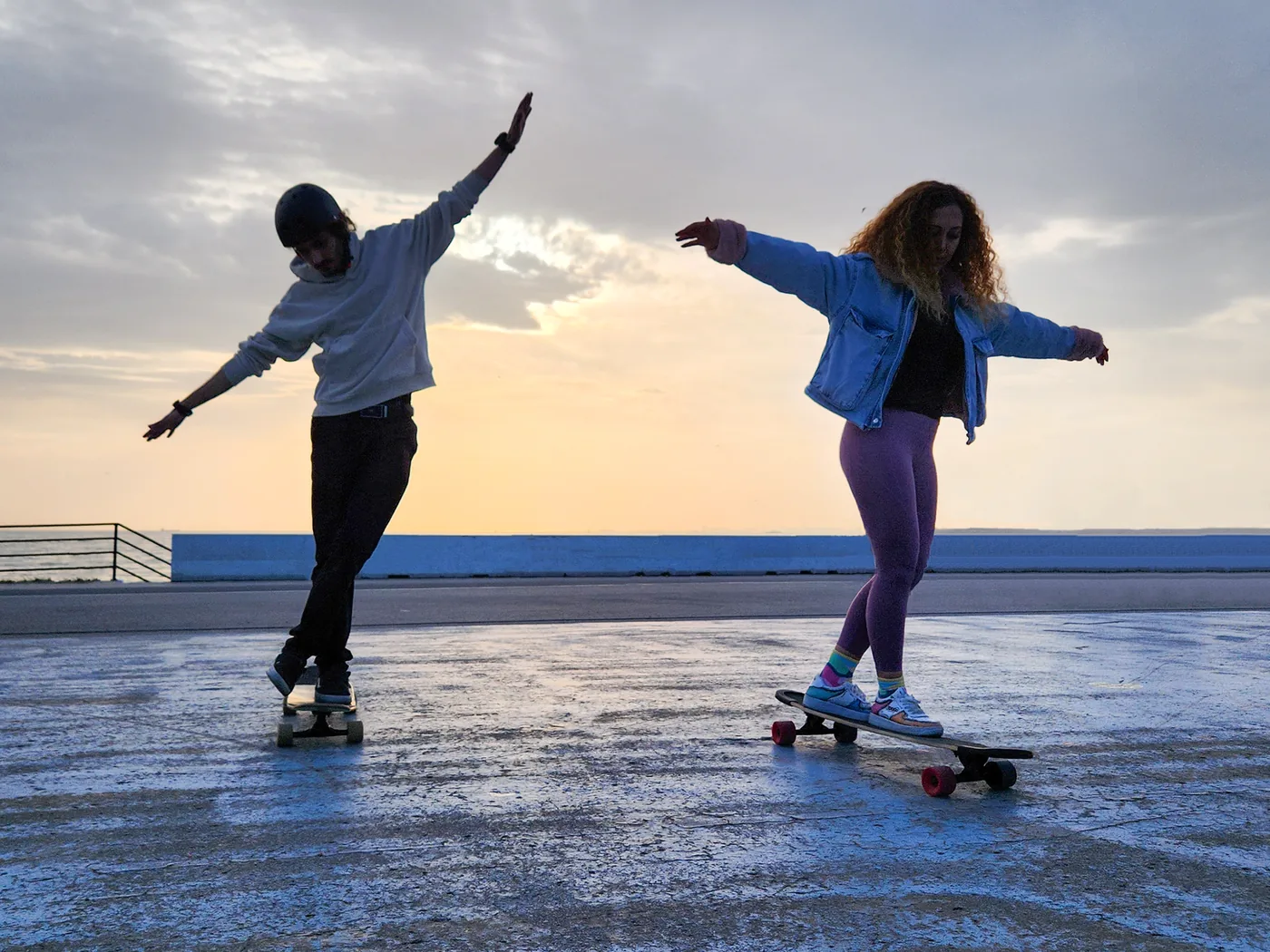 dvojice jede na skateboardu při západu slunce