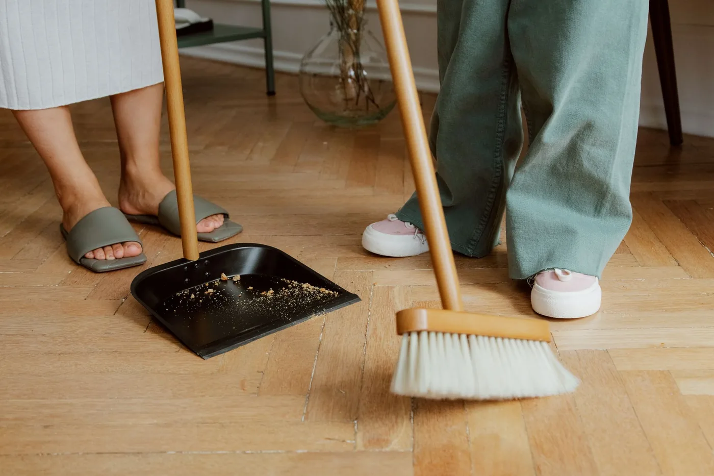 dvojice zametá podlahu koštětem a lopatkou