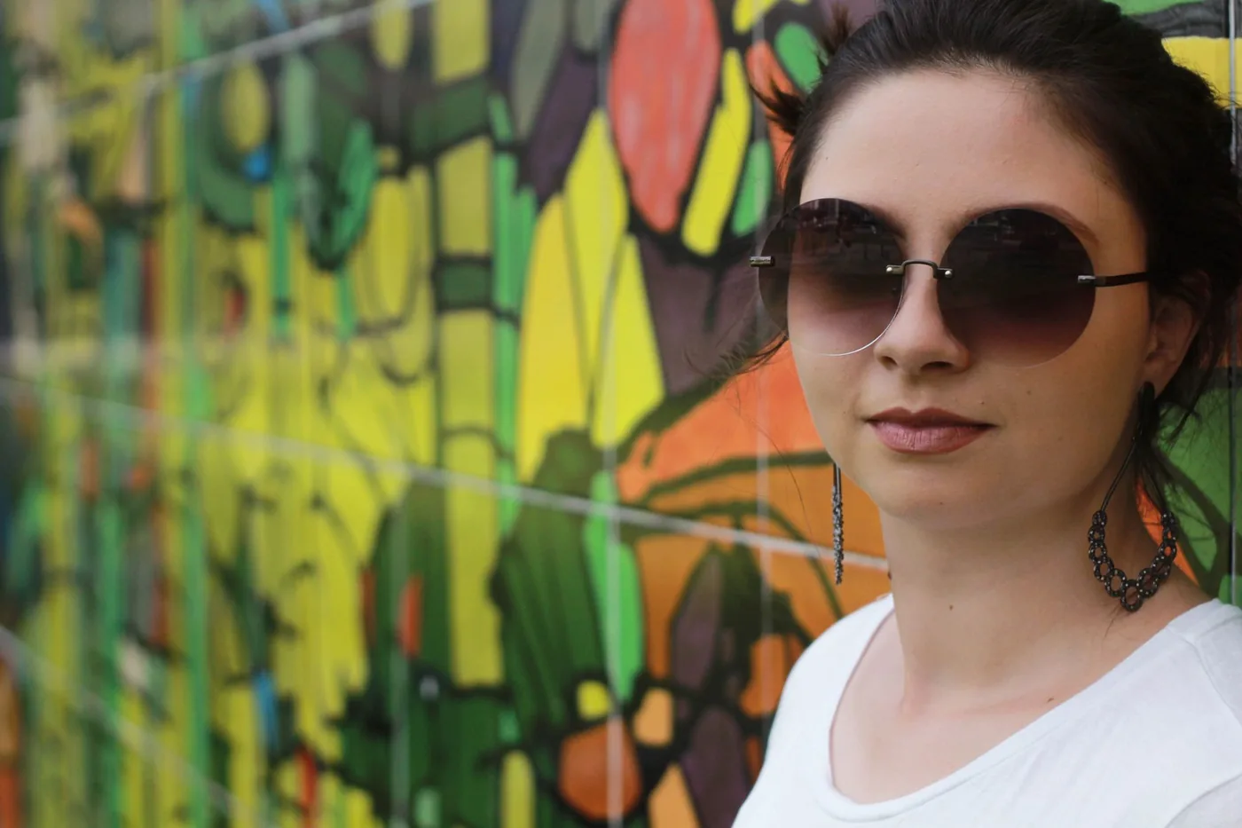 žena v slunečních brýlích před graffiti zdí