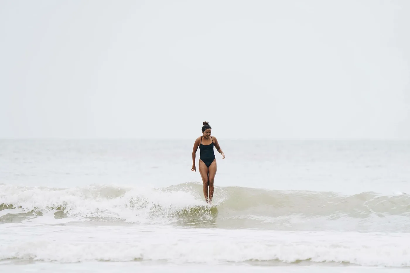žena v jednodílných plavkách surfuje na vlnách