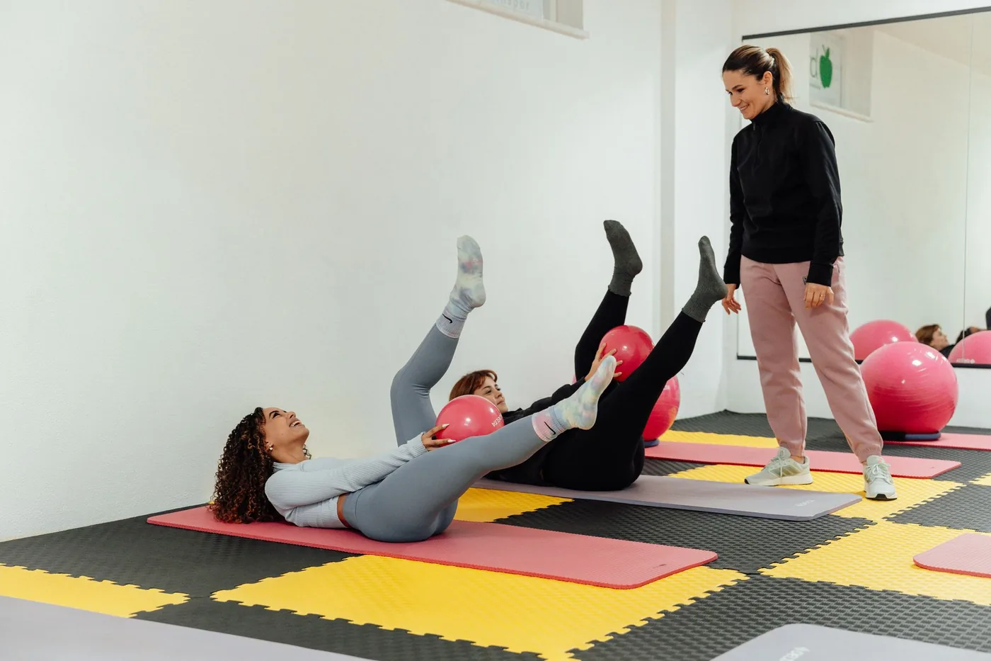 ženy cvičí pilates s míčky na podložce