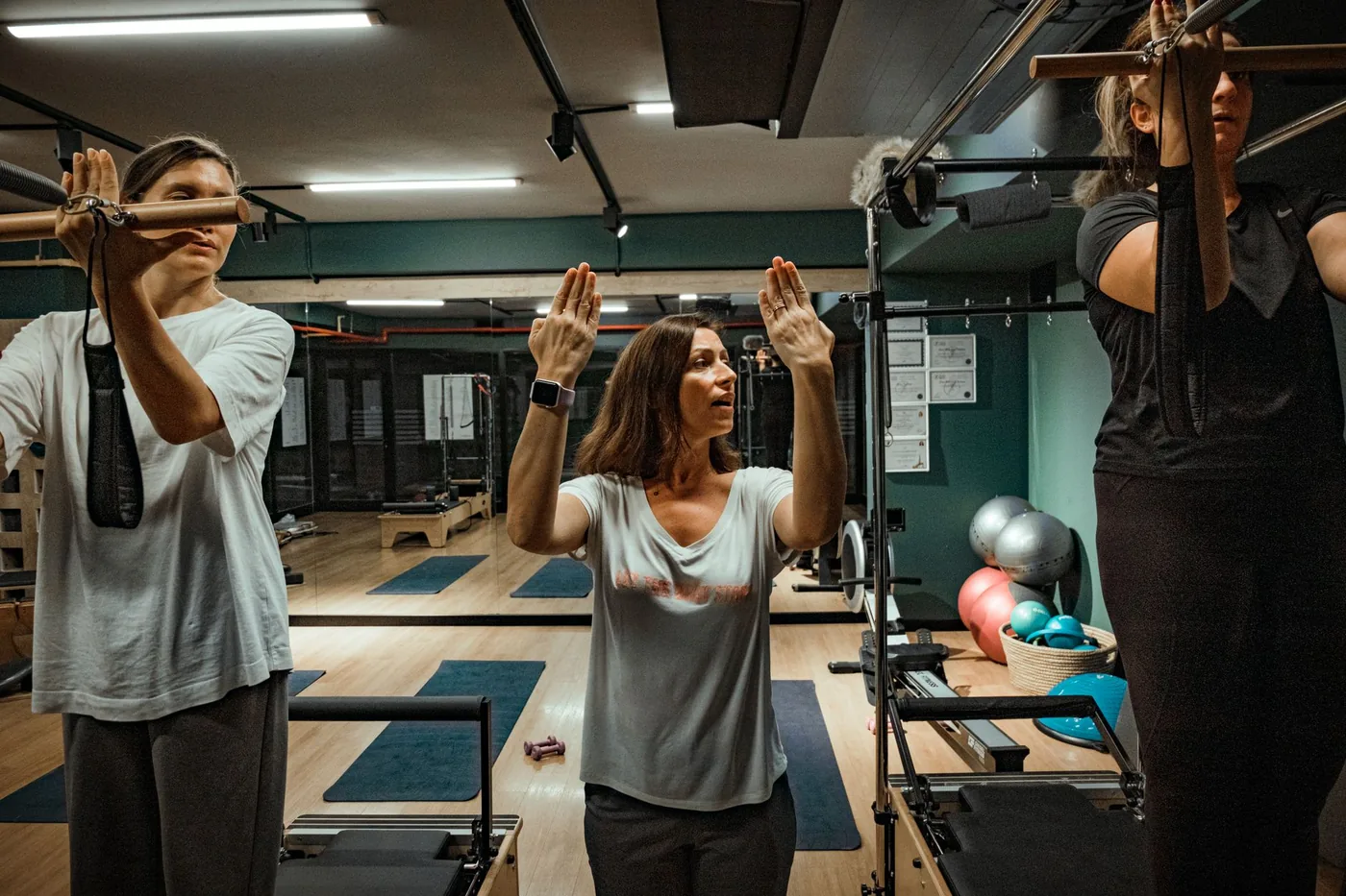 skupina lidí cvičí pilates se zvednutýma rukama