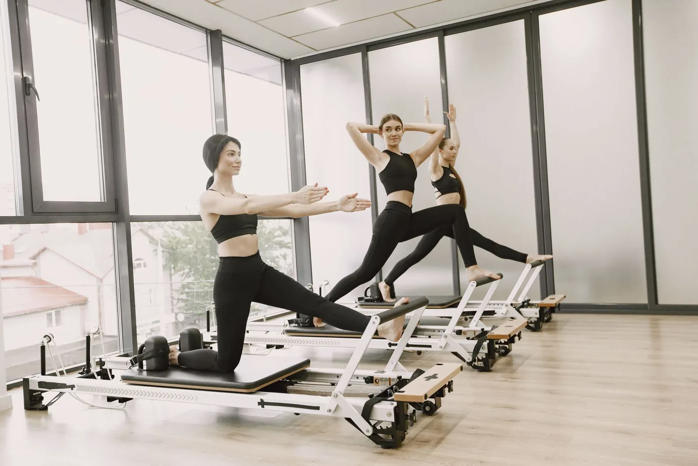 tři ženy cvičí na pilates reformerech