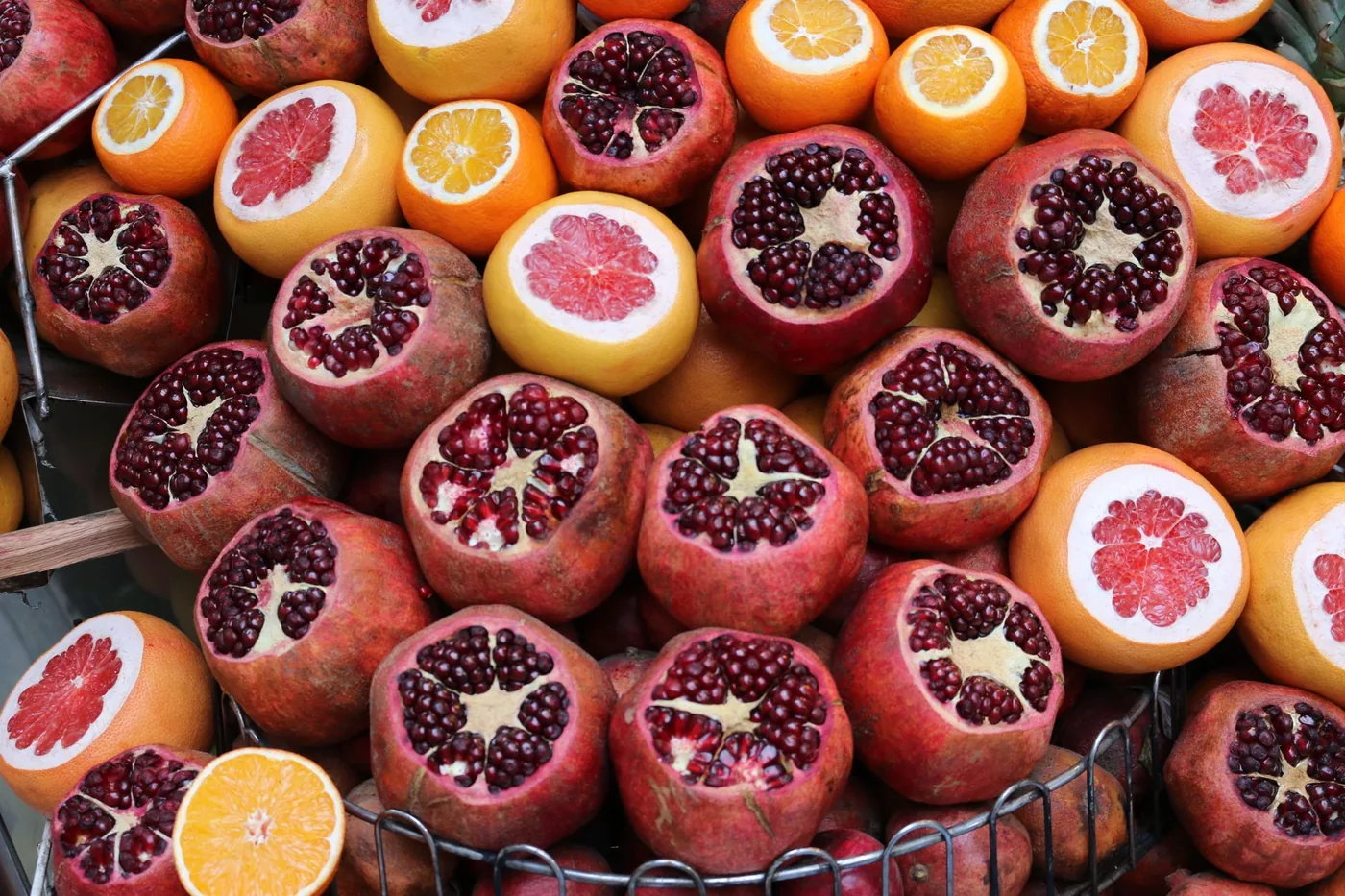 rozkrojená granátová jablka a citrusy