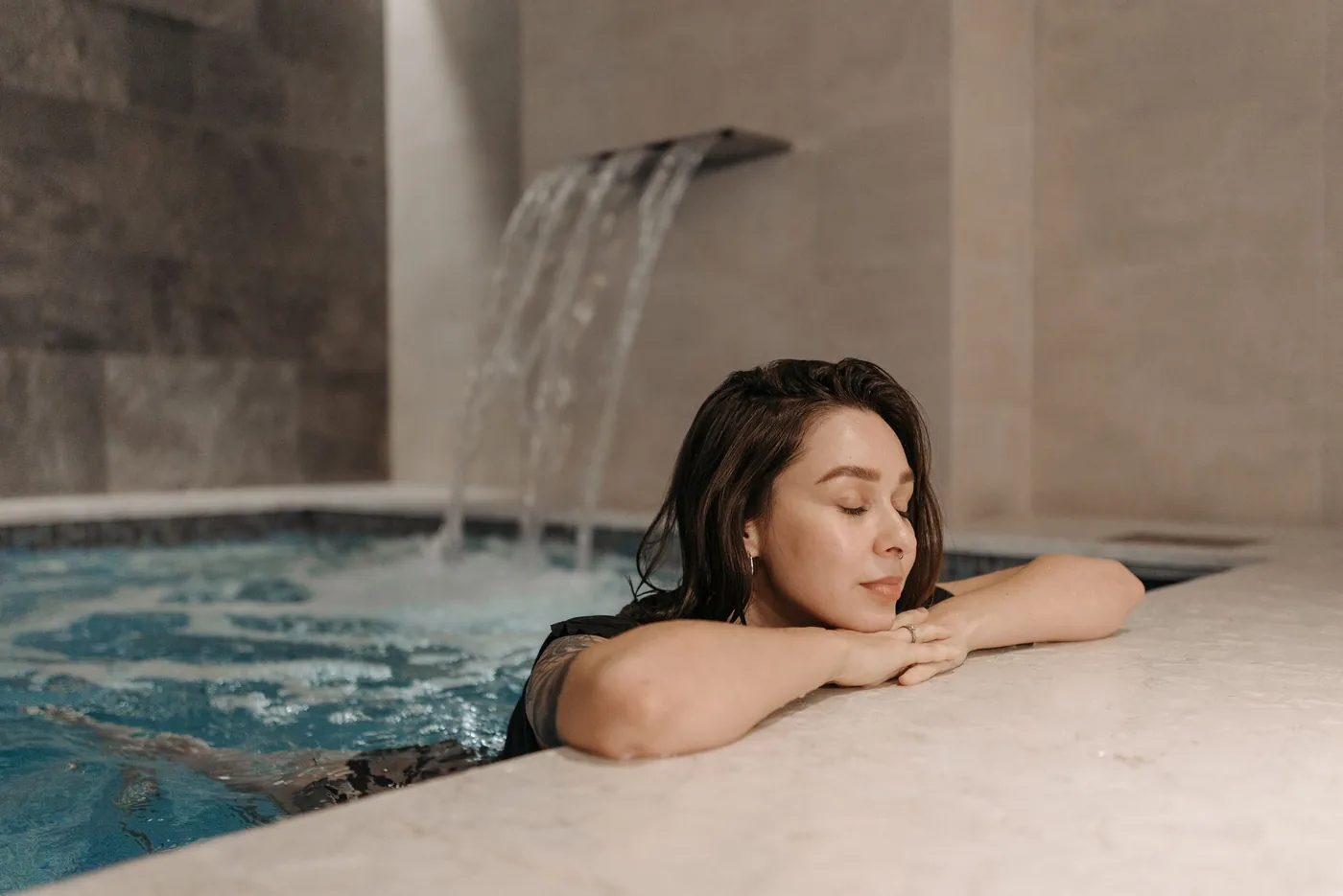 žena relaxuje ve wellness bazénu s vodopádem